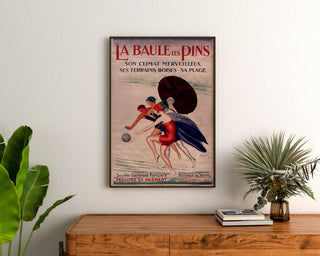 Bretagne-vintageaffisch – La Baule-les-Pins, inramad ovanför ett träbyrå, mellan växter.