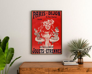 Vintage reklamaffisch Paris–Dijon, leksaker och gåvor, inramad ovanför en träbyrå, mellan växter.