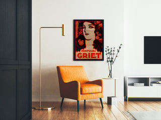 Vintage reklamaffisch Perfumes Griet, inramad i ett vardagsrum med en orange fåtölj och en golvlampa.