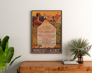 Vintagereklamaffisch Potasses d’Alsace, inramad ovanför en byrå i trä, mellan växter.