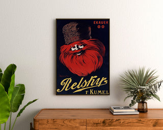 Vintage reklamaffisch Relskyr - 1° Kumel, inramad ovanför en träbyrå mellan gröna växter.