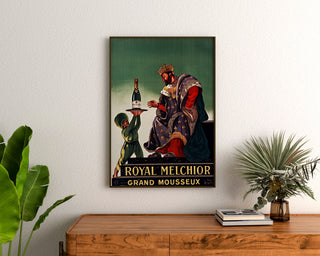 Vintage reklamaffisch Royal Melchior, grand mousseux, inramad ovanför en träbyrå mellan växter.