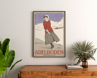 Schweizisk vintageaffisch – Adelboden – Carlo Pellegrini, 1905, inramad ovanför ett träbyrå, mellan växter.