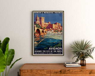 Vintage turistaffisch – Avignon, romansk och medeltida Frankrike, inramad ovanpå en träbyrå, mellan växter.