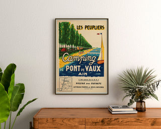Vintage turistaffisch – Les Peupliers, camping i Pont‑de‑Vaux, inramad ovanför en träbyrå mellan växter.