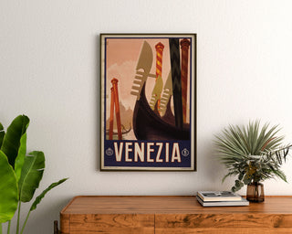 Vintage turistaffisch – Venezia, gondolernas förstävar, inramad ovanför en träbyrå mellan växter.