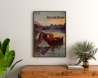 Vintage affisch Aix-les-Bains, PLM kollektiva biljetter, inramad ovanför en träbyrå, mellan växter.