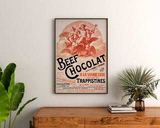 Vintage affisch Beef Chocolat, chocolaterie de la Drôme, inramad ovanför en träbyrå, mellan växter.