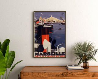 Vintageaffisch Marseille, Porte de l’Afrique du Nord, inramad ovanför en byrå i trä, mellan växter.