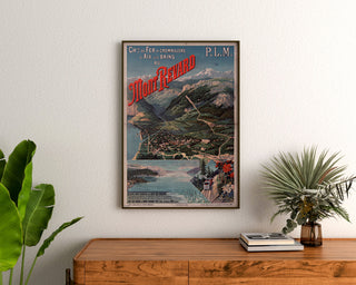Vintageaffisch Mont-Revard, tandhjulsjärnväg, inramad ovanför en träbyrå, mellan växter.