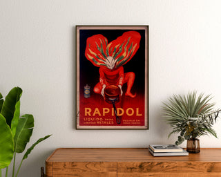 Vintage affisch Rapidol, inramad ovanför en träbyrå mellan växter.