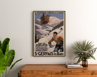 Vintageaffisch Saint-Gervais, Mont-d’Arbois, inramad ovanför en träbyrå, mellan växter.