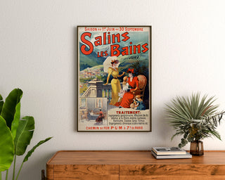 Vintageaffisch Salins les Bains (Jura), inramad ovanför en träbyrå, mellan växter.