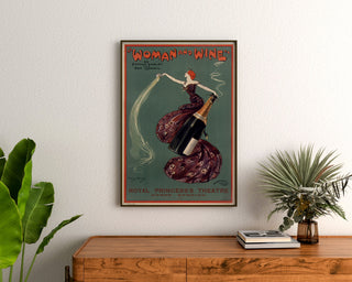 Vintageaffisch Woman and Wine, Princess’s Theatre, inramad ovanför en träbyrå mellan växter.